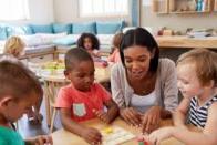 Teacher helping children learn to put blocks into a puzzle.